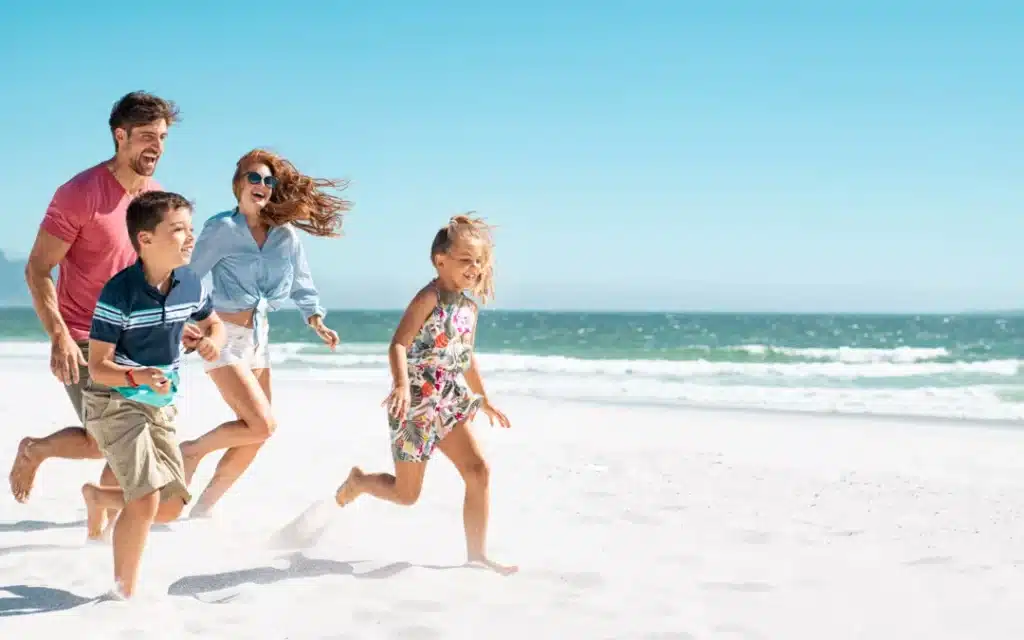 Happy family running together on a sandy beach