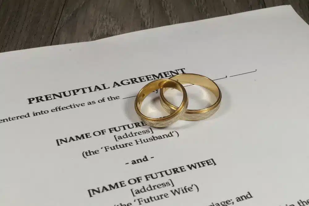 a prenuptial agreement with 2 wedding rings on table